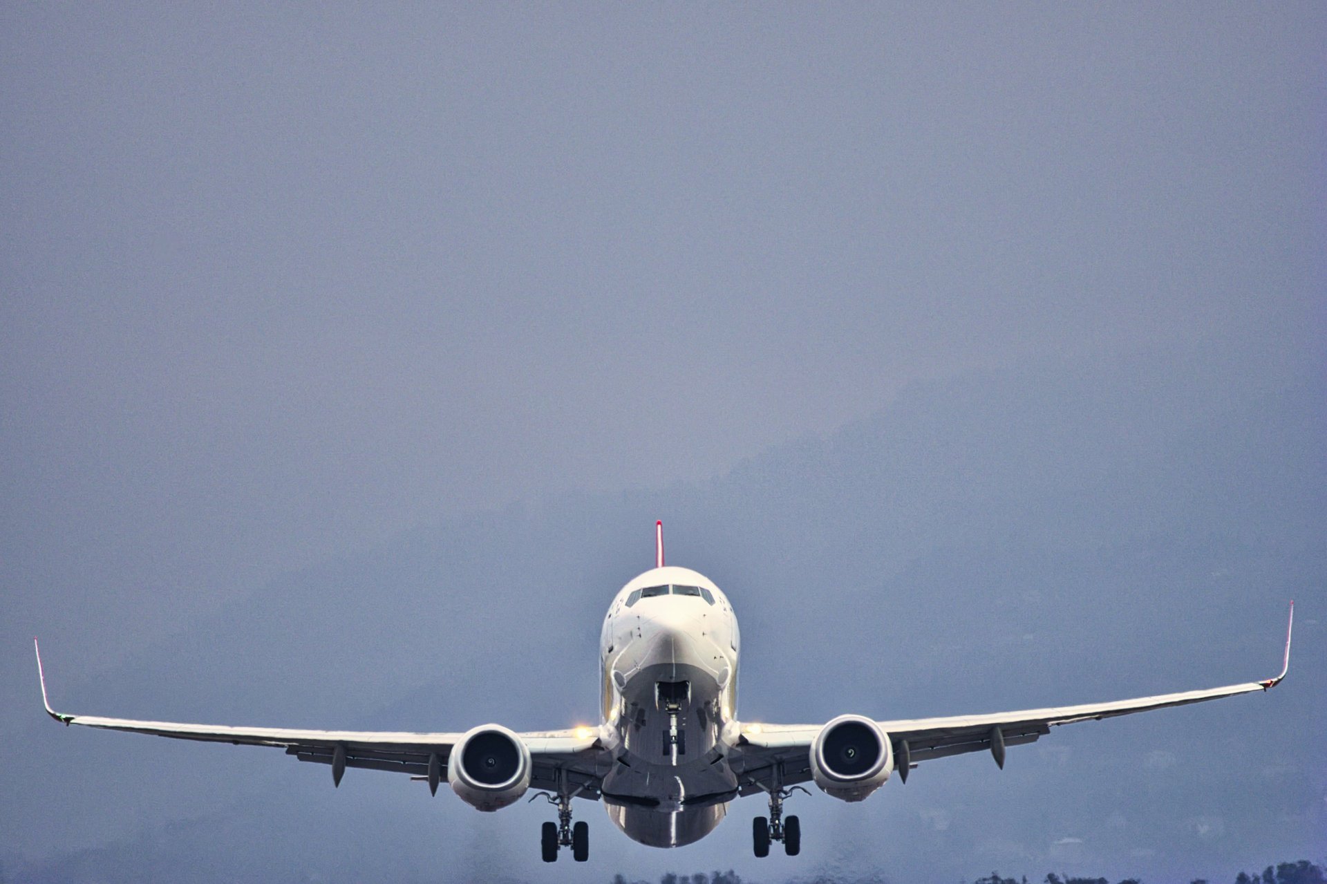 Commercial jet on final approach with landing gear extended against a moody sky